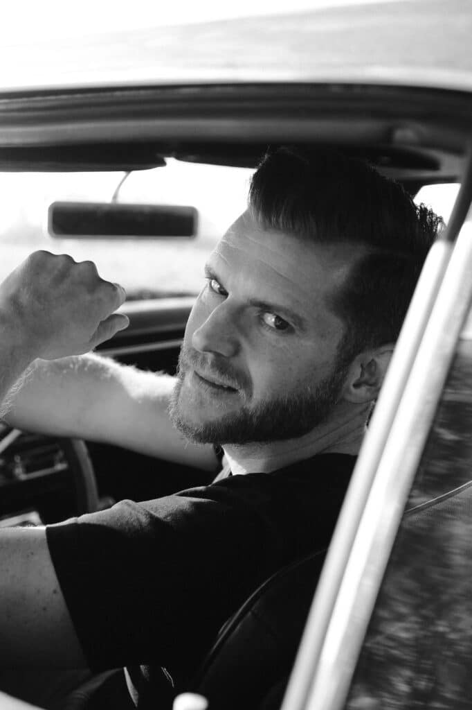Mann mit Bart sitzt am Steuer eines Autos – Schwarzweiß Charakterportrait
