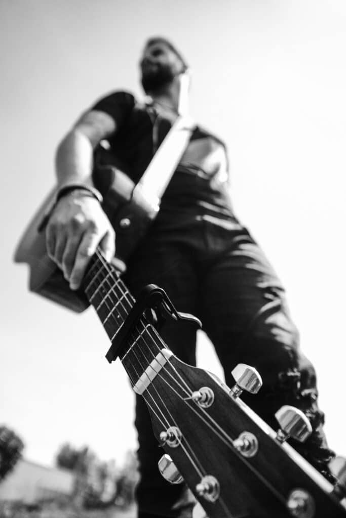 Mann mit Gitarre aus der Froschperspektive fotografiert – Schwarzweiß Portrait