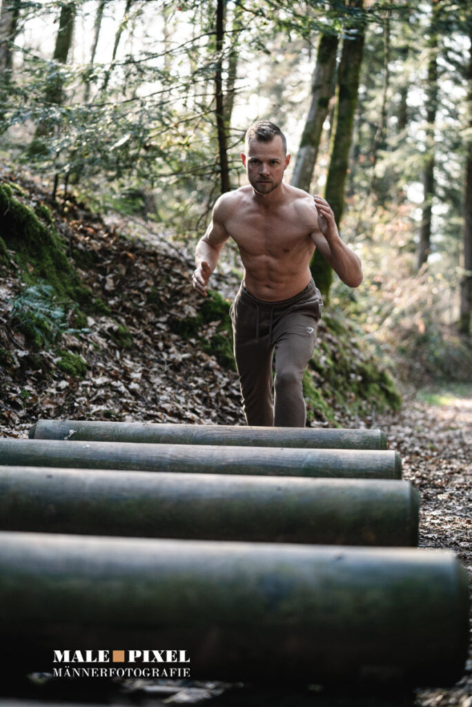 Calisthenics Outdoor Workout mit Klimmzügen, Ringen und Bodyweight Training im Wald mit sportlichem Mann