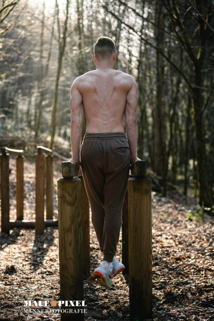 Calisthenics Outdoor Workout mit Klimmzügen, Ringen und Bodyweight Training im Wald mit sportlichem Mann