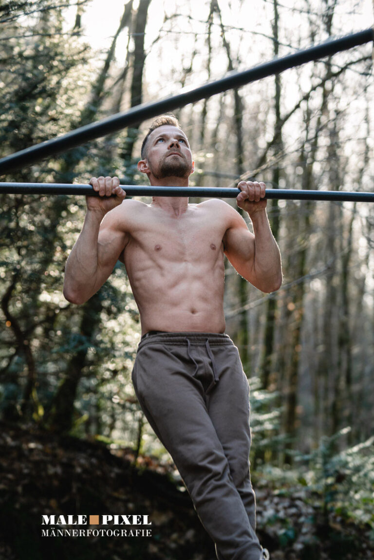 Calisthenics Outdoor Workout mit Klimmzügen, Ringen und Bodyweight Training im Wald mit sportlichem Mann