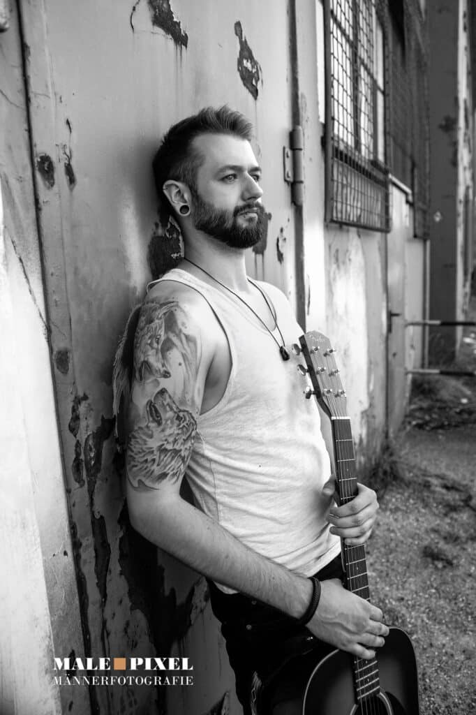 Männerportrait mit Gitarre an Wand