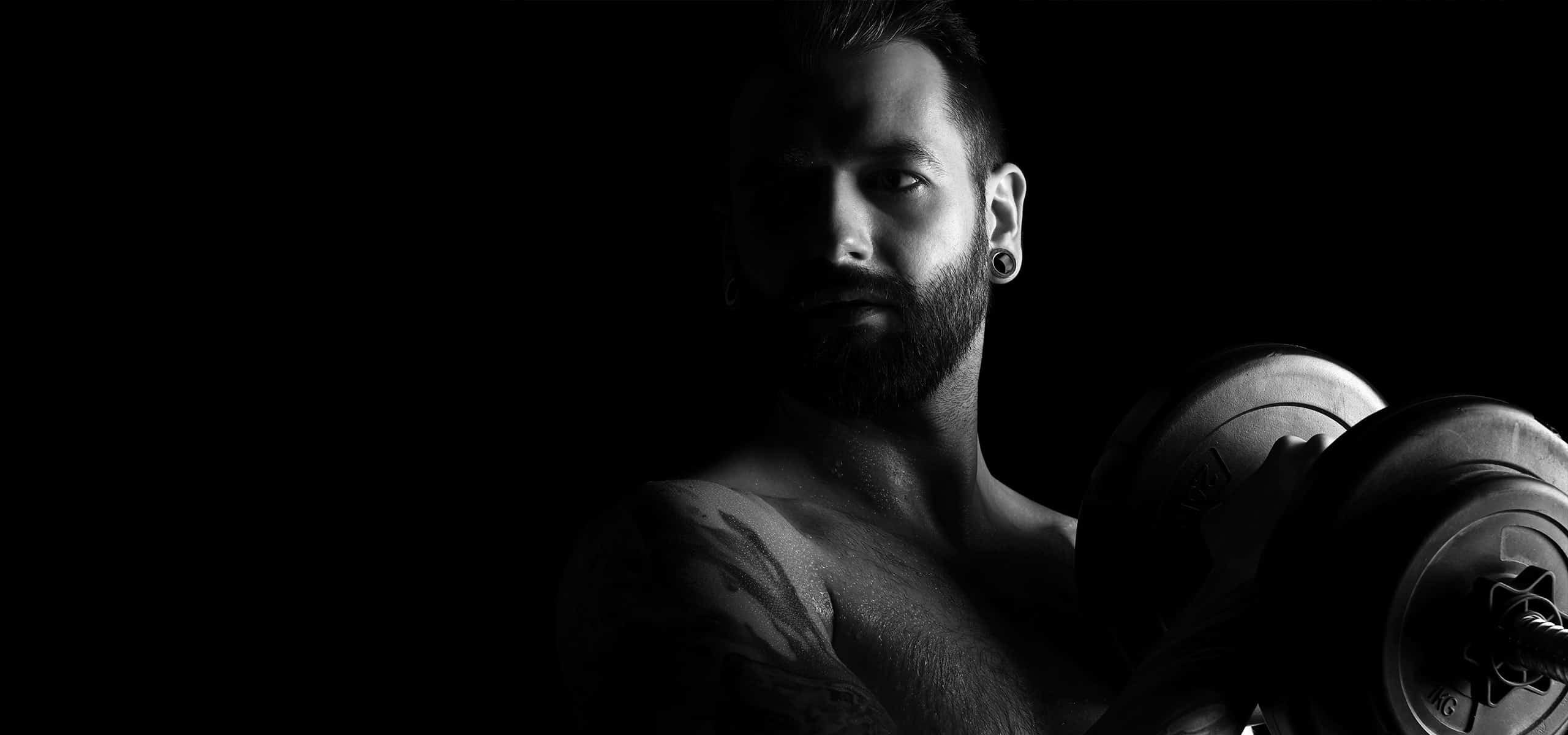Sportlicher Mann trainiert mit Hantel im Low-Key-Licht – Schwarzweiß Fitnessportrait