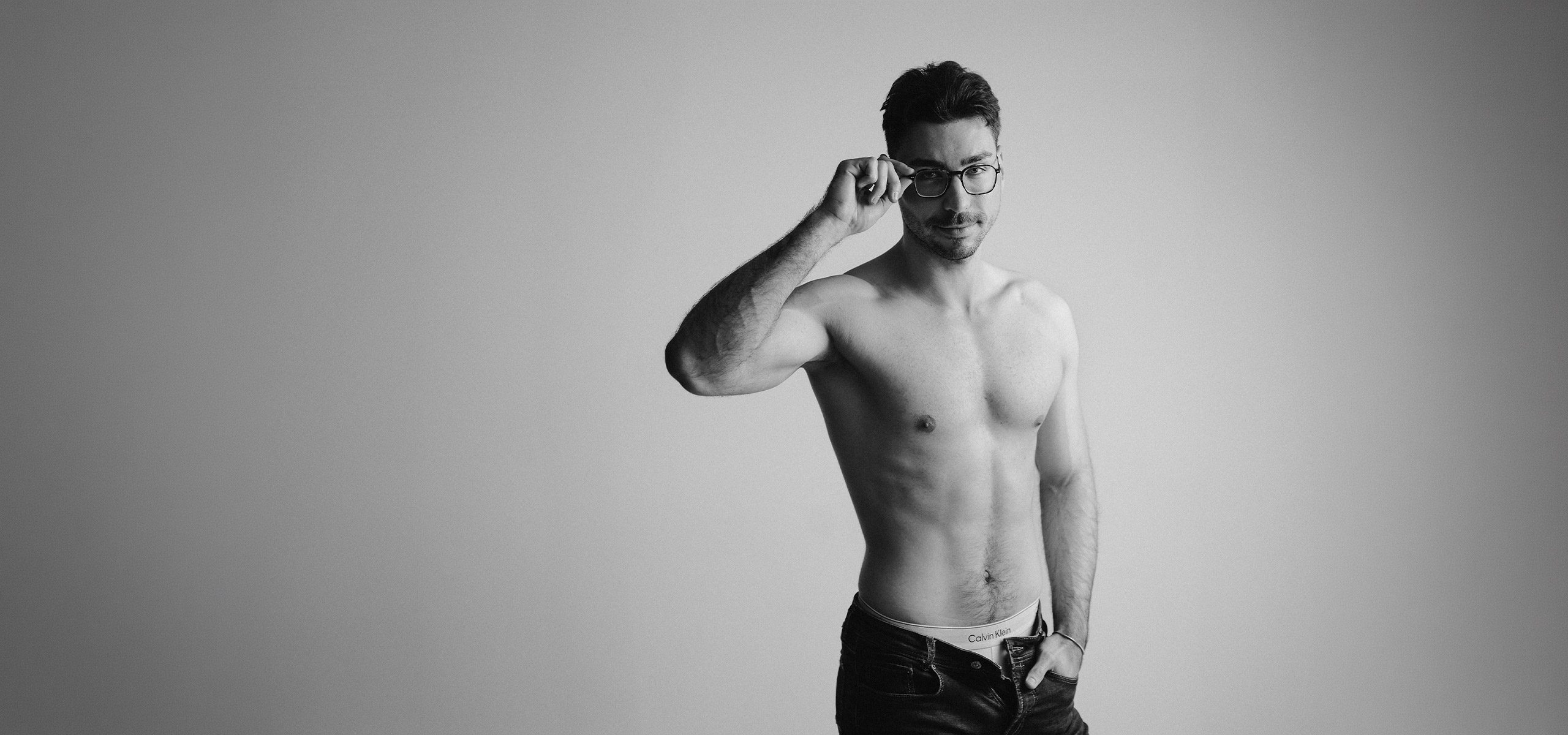 Sportlicher Mann mit Brille und freiem Oberkörper – Schwarzweiß Studio Portrait